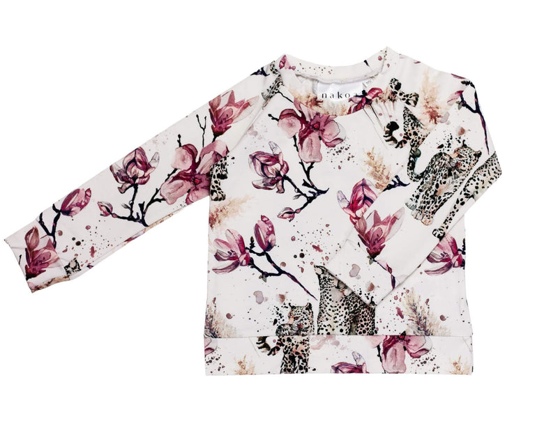 Magnolia print paita Nakoa. Nakoan lumoavassa Magnolia-printissä yhdistyvät rouheat magnolian kukat sekä elegantit lumileopardit. Magnolia-printissä on harmoninen värimaailma, kun kukkien vanha roosa on yhdistetty kauniin nuden eri sävyihin. Nakoa Print Shirt on rennon mallinen, mukava arkivaate GOTS-sertifioidusta puuvillatrikoosta. Lastenvaatteet on suunniteltu Suomessa ja valmistettu Euroopassa.